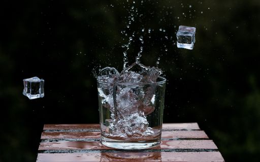 A splash from ice cubes in a glass of refreshing drink on a blurred background