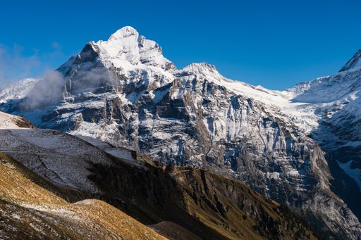 A beautiful scenery of high rocky mountains covered with snow under a clear blue sky in Switzerland