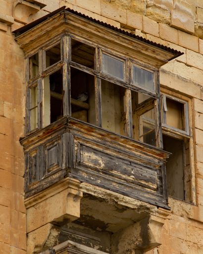 A vertical low angle shot of the derelict balcony of the old building
