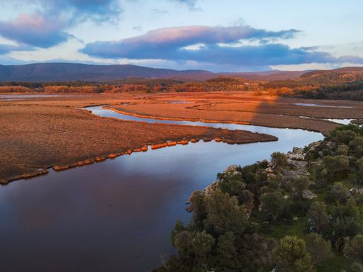 An aerial view of a river flowing through a valley during sunset