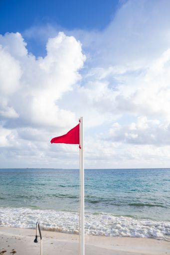 A red flag on a sandy beach on a sunny morning