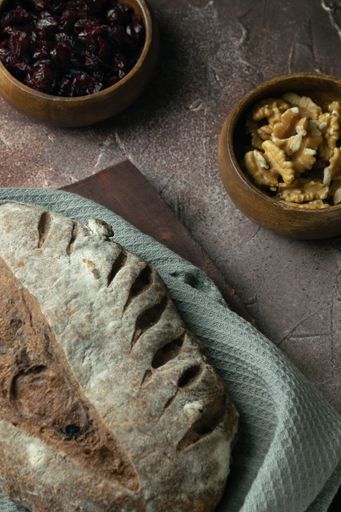 A vertical closeup of a loaf of rustic bread with nuts and raisins.