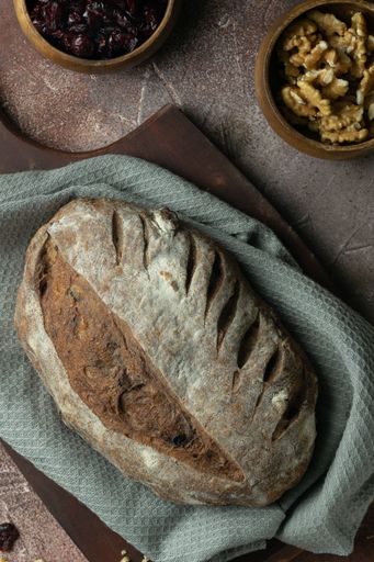 A vertical closeup of a loaf of rustic bread with nuts and raisins.
