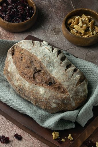 A vertical closeup of a loaf of rustic bread with nuts and raisins.