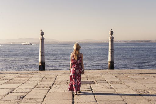 A landscape shot of a young female traveler enjoying the view in Cais das Colunas Lisbon Portugal