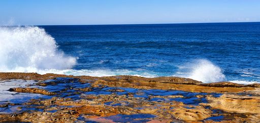 A panoramic shot of cliffs near the sea under a blue cloudy sky