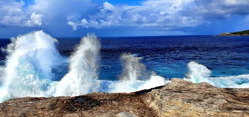 A panoramic shot of cliffs near the sea under a blue cloudy sky