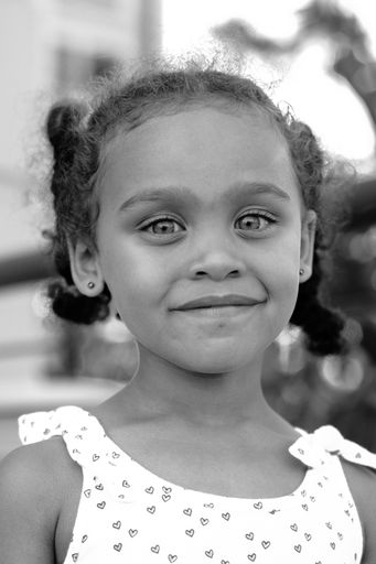 a vertical shot of small girl smiling in grayscale
