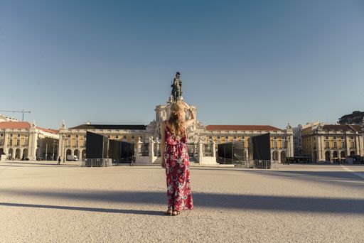 A young female in a floral dress walking around the Commerce Square in Lisbon, Portugal