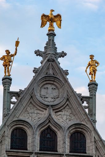 A vertical shot of a flemish historical building with French Imperial Eagle and two sculptured soldiers in Antwerp, Belgium