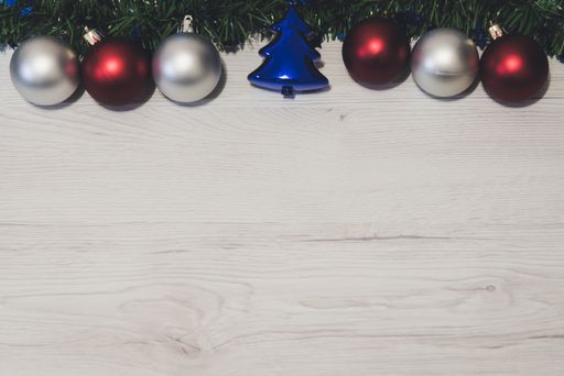 An overhead top view of colorful Christmas ornaments hanging on a fir branch on a wooden background