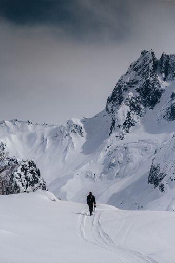 a photo of man walking in snaw against of mountain