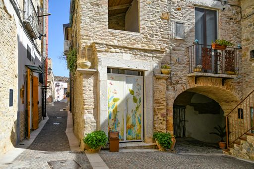 A beautiful shot of narrow street between the houses of a medieval village in the Puglia region on a sunny day, Ascoli Satriano, Italy