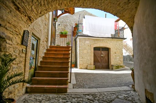 A beautiful shot of narrow street between the houses of a medieval village in the Puglia region on a sunny day, Ascoli Satriano, Italy