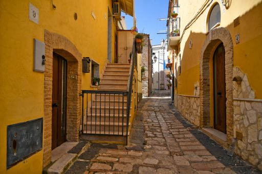 A beautiful shot of narrow street between the houses of a medieval village in the Puglia region on a sunny day, Ascoli Satriano, Italy
