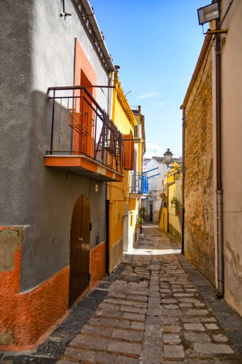 A beautiful shot of narrow street between the houses of a medieval village in the Puglia region on a sunny day, Ascoli Satriano, Italy