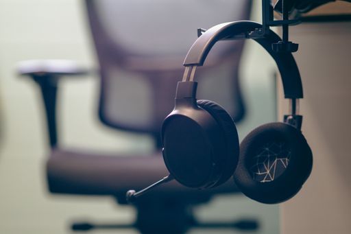 The close-up of a black Headphone hanging and an office chair in the background
