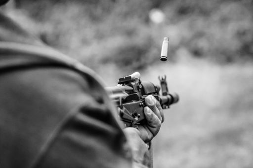 A closeup of a man with a gun in a forest