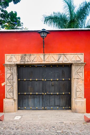 Colonial style house facade in the city of La Antigua Guatemala, with fireplace and wrought iron balconies, cobblestone street and blue sky, natural l