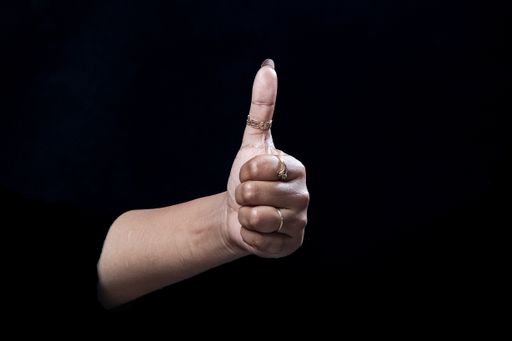 A thumbs up hand gesture isolated on black background
