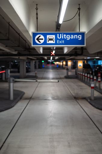 A vertical shot of an exit sign in a car parking lot of an airport in The Netherlands