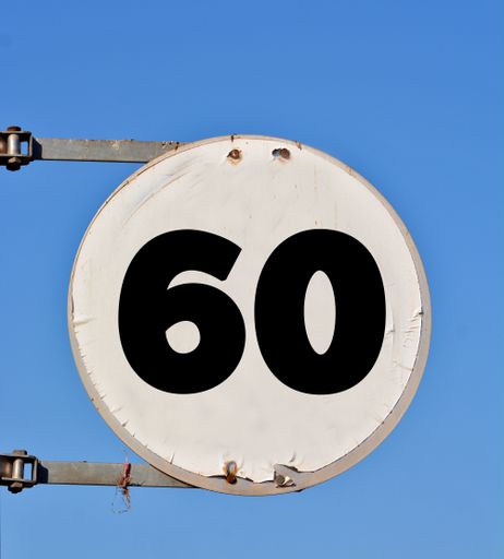 A speed limit sign with number 60 added on it against a blue sky