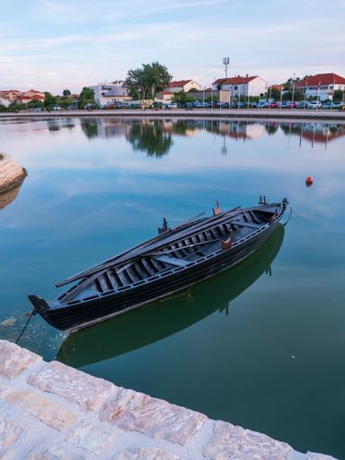 A vertical shot of a wooden boat on the shore of Nin, Dalmatia, Croatia