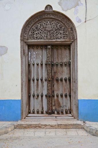 An arch-shaped wooden door on the streets of Zanzibar, Tanzania, Africa