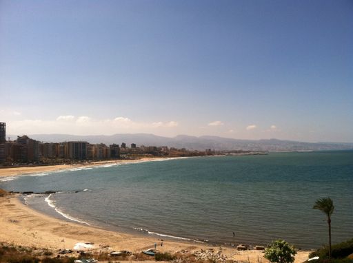 A high angle shot of the beautiful blue sea and high-rise buildings on the seashore under the cloudy sky