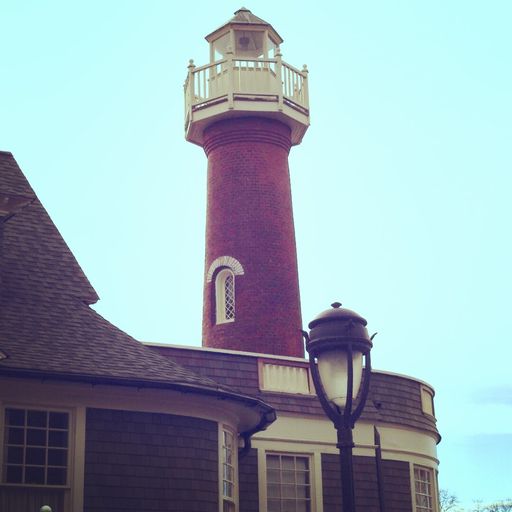 A low angle shot of a lighthouse with street lights under the clear blue sky