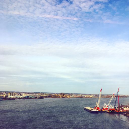 A vertical shot of the beautiful sea with a lot of buildings on the shore and small ships under the cloudy sky