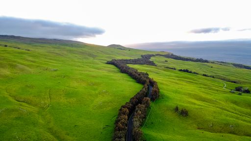 An aerial view of a countryside with green grass under the cloudy skies