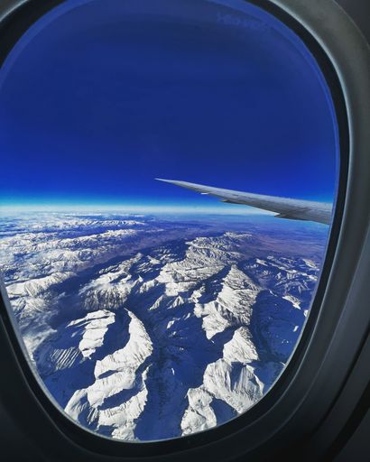 A vertical view at snowy landscapes from an airplane's window