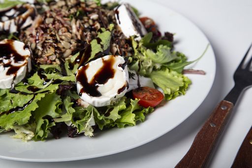 A delicious salad with sunflower seeds lettuce tomatoes and burrata cheese glazed with balsamic vinegar