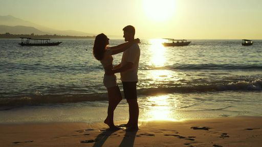 A romantic couple enjoying their time together on the beach at sunset on Gili Islands, Indonesia