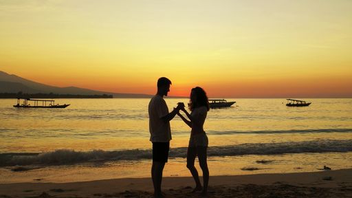 A romantic couple enjoying their time together on the beach at sunset on Gili Islands, Indonesia