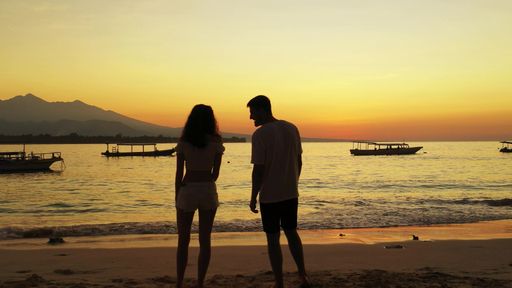 A romantic couple enjoying their time together on the beach at sunset on Gili Islands, Indonesia