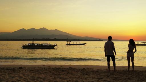 A silhouette shot of a Caucasian couple watching the sunset on the beach in Gili Meno, Indonesia