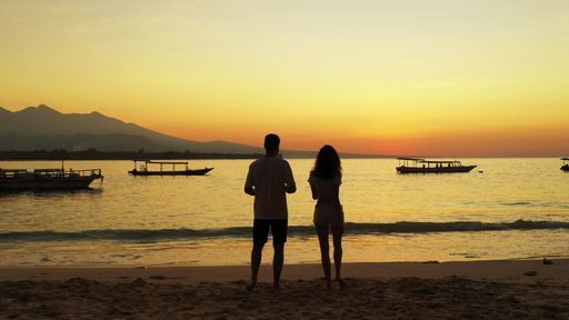 A silhouette shot of a Caucasian couple enjoying the sunset on the beach in Gili Meno, Indonesia