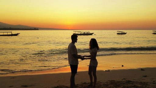 A silhouette shot of a Caucasian couple holding hands at sunset on the beach in Gili Meno, Indonesia
