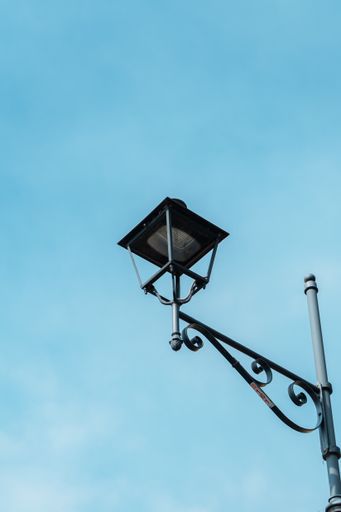 A vertical low angle shot of a vintage lamp in a blue sky