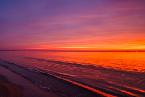 A beautiful shot of a colorful sunset over the beach with calm waves