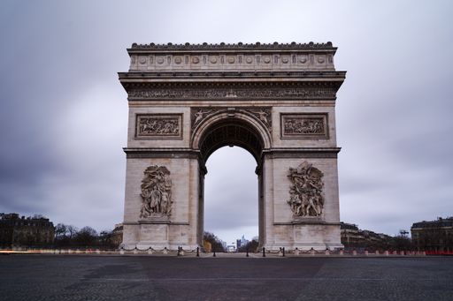 A beautiful shot of the Arc de Triomphe against a cloudy gray sky in Paris, France
