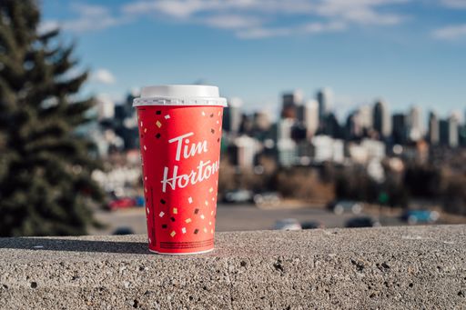 Red Tim Hortons cup on a cement wall with the cityscape in the background