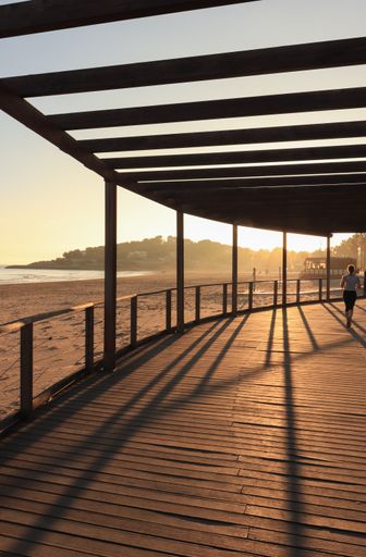 A beautiful view of female jogging on the terrace on the beach with a sunset background