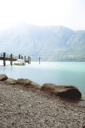 A vertical shot of a calm lake captured from the wet sandy coast in spring