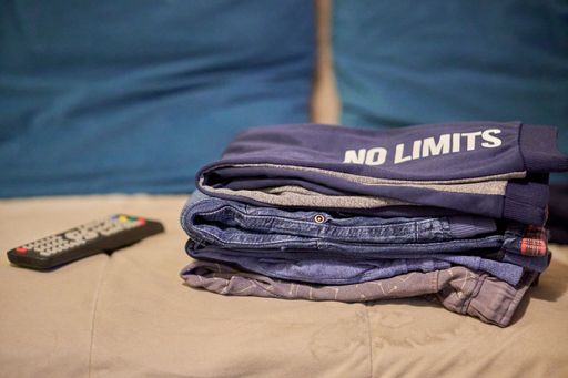 A closeup shot of ironed folded clothes on a sofa near a remote control