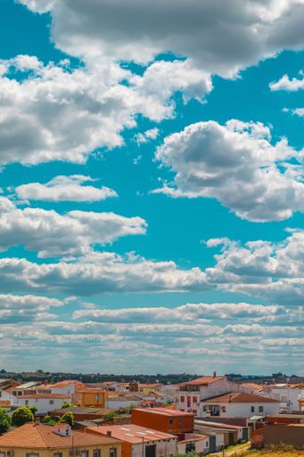 A vertical shot of the buildings of the city under the sky full of clouds