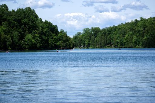 A seascape of the blue lake surrounded with green forests and small kayaks in the lake