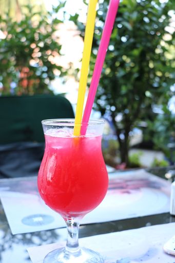A vertical closeup shot of a fresh pink cocktail with two straws on a table